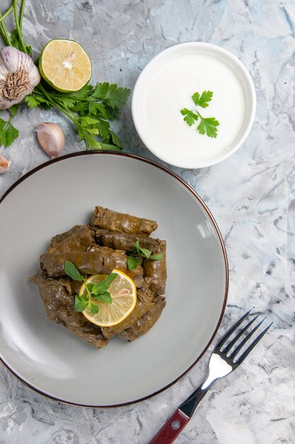 Top view of green leaf dolma with greens on a white surface