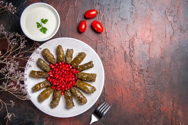 Top view of green leaf dolma with pomegranates on dark surface