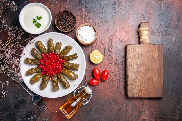 Top view of green leaf dolma with seasonings on a dark surface