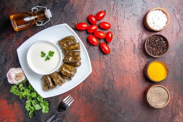 Top view of green leaf dolma with seasonings on dark surface