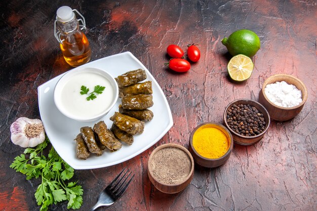 Top view of green leaf dolma with seasonings on dark surface