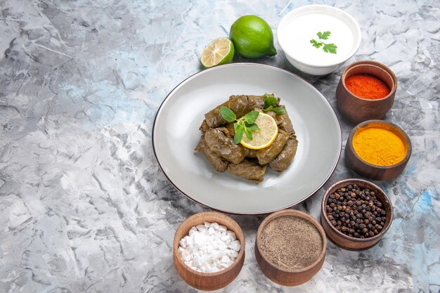 Top view of green leaf dolma with seasonings on white surface