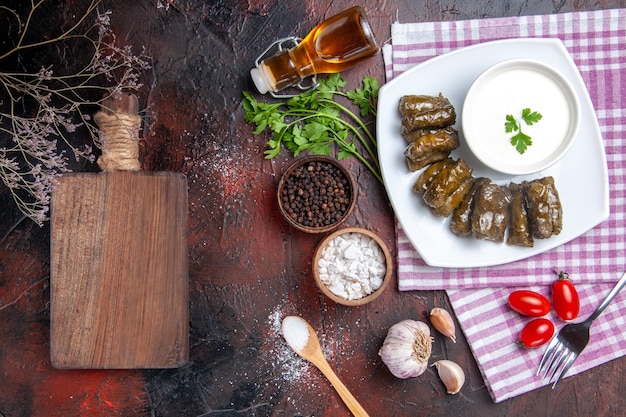 Top view of green leaf dolma with yogurt on dark surface