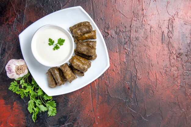 Top view of green leaf dolma with yogurt on dark surface