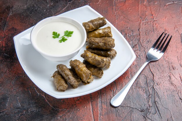 Top view of green leaf dolma with yogurt on the dark surface