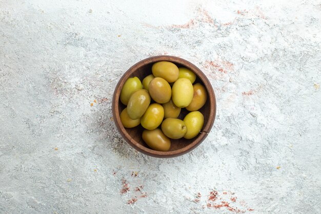 Top view green olives inside little plate on white space