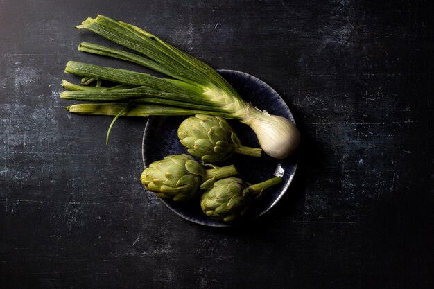 Top view green onion and artichoke in bowl