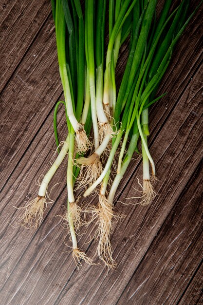 Top view of green onions on wooden background with copy space