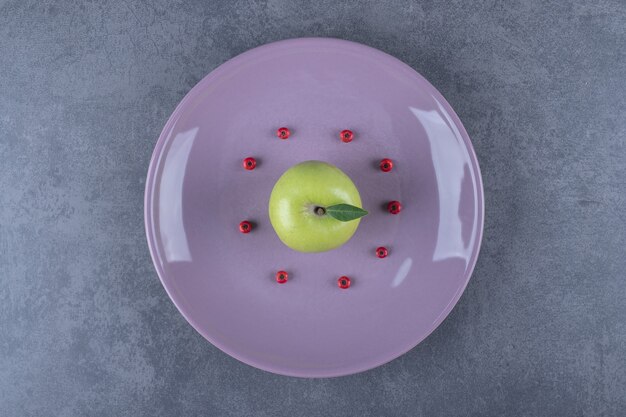 Top view of Green organic Fresh apple on purple plate.