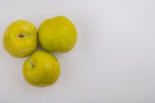 Top view of green pluots on white background with copy space