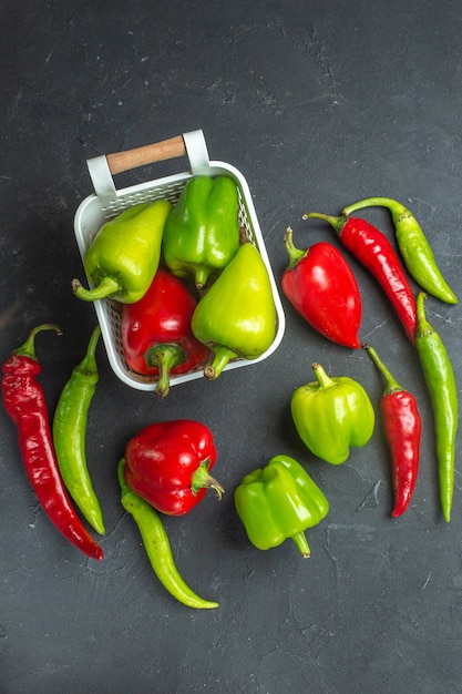 Top view green and red peppers in plastic basket hot peppers on dark surface
