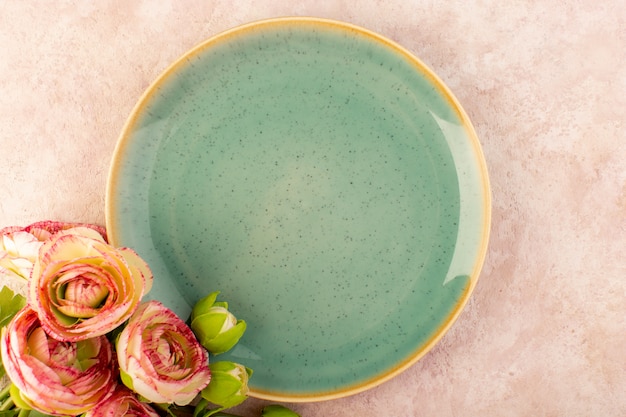 A top view green round plate along with flowers food table