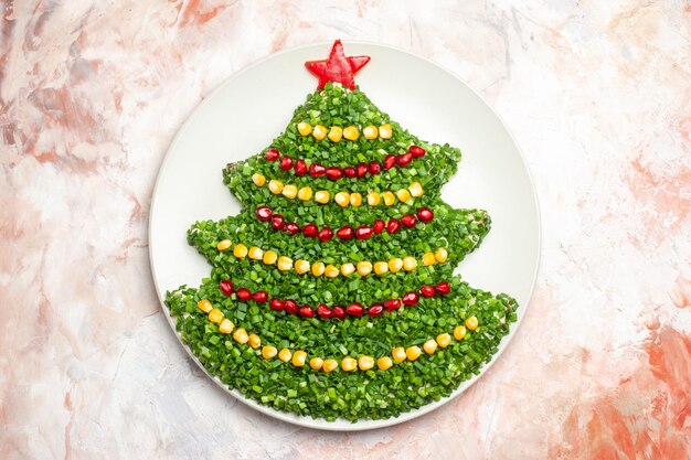밝은 배경에 있는 접시 안에 있는 새해 나무 모양의 상위 뷰 그린 샐러드