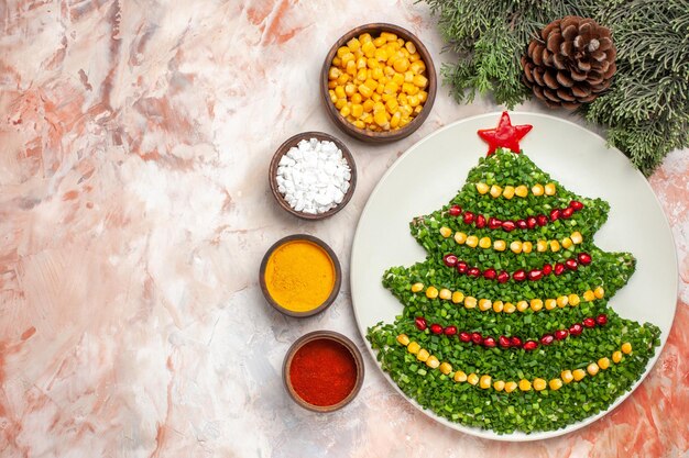 Top view green salad in new year tree shape with seasonings on light background