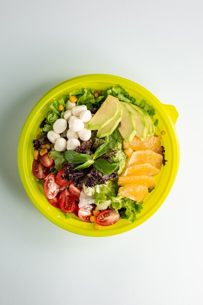 Top view of green salad with lettuce cherry tomato avocado orange corn and mozzarella