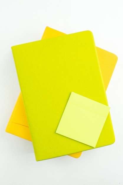 Top view green sticky note on colorful notebooks on white table