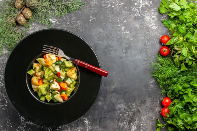 Top view green tomato salad a fork on oval plate greens tometoes on dark background