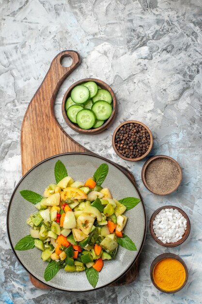 Top view green tomato salad on oval plate on cutting board different spices on dark background