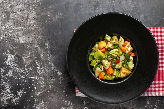 Top view green tomato salad on oval plate on dark background