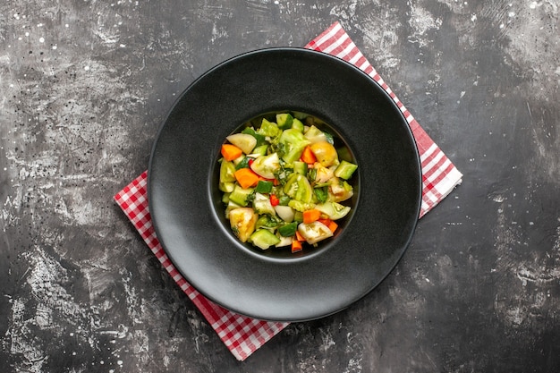 Top view green tomato salad on oval plate on napkin on dark background