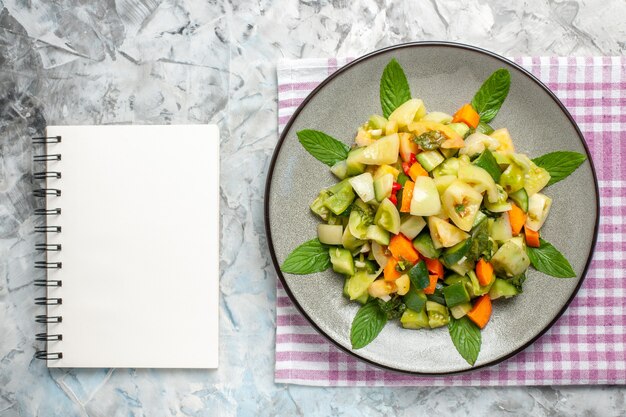 Top view green tomato salad on oval plate a notepad on dark background