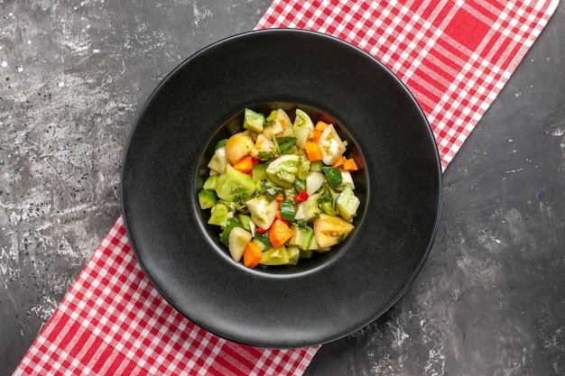 Top view green tomato salad on oval plate on tablecloth on dark background