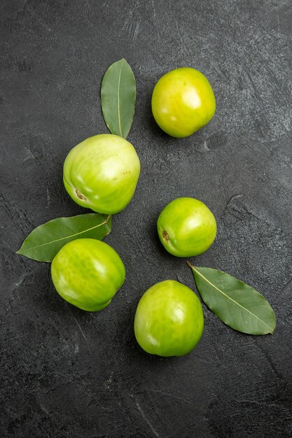 Top view green tomatoes and bay leaves on dark surface