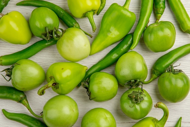 Top view green tomatoes with peppers on white desk