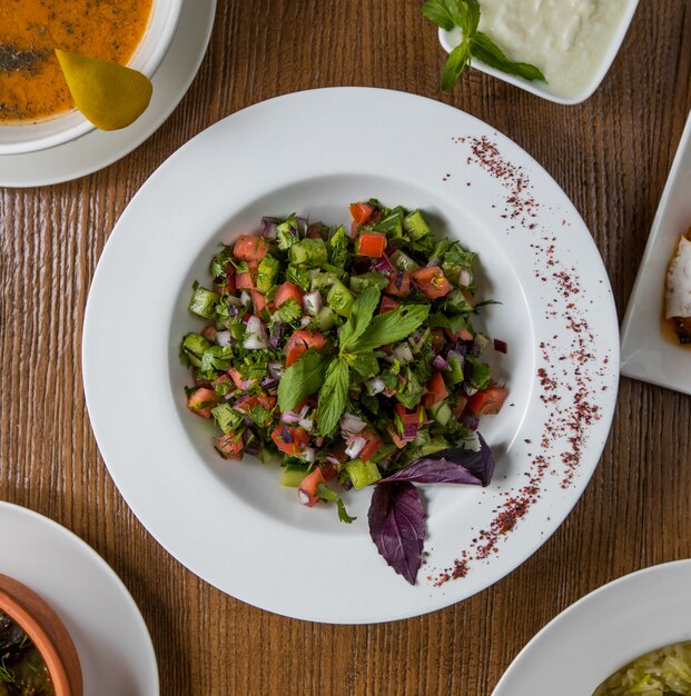 Top view green vegetables salad with cubes inside white plate.