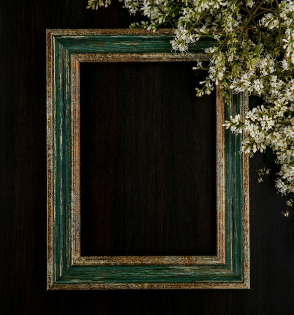 Top view of greenish gold frame with flowers on a black surface