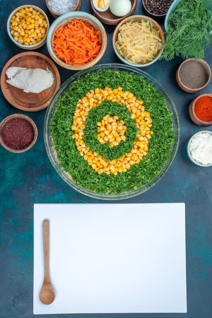 Top view greens salad with corns along with with seasonings and eggs on dark blue desk.