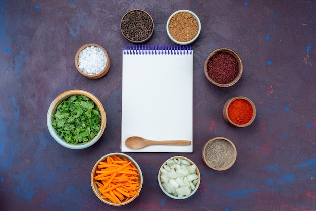 Top view greens and seasonings with sliced onions and notepad on dark desk salad food meal vegetable snack