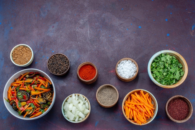 Top view greens and seasonings with sliced onions and vegetable salad on the dark desk salad food meal vegetable snack