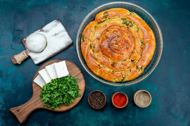 Top view greeny pastry with greens inside with cheese and greens on dark background.