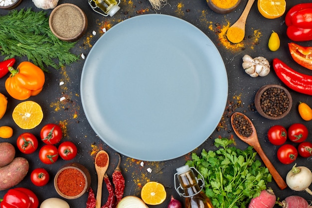 テーブルの上の灰色の丸いプレートの新鮮な野菜とスパイスの上面図