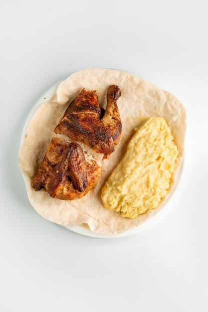 Top view of grilled chicken half and mashed potatoes served on flatbread