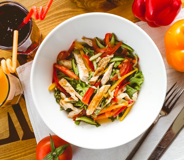 Top view grilled chicken salad with bell pepper tomato lettuce cucumber on the table