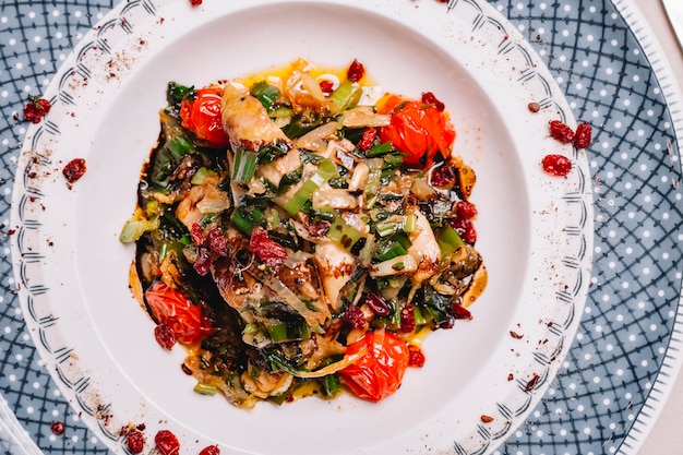 Top view grilled chickien with fried onion tomato bell pepper and greens on a plate