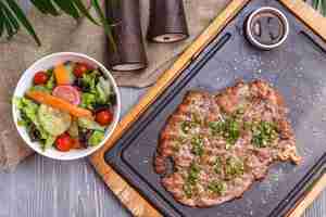 Foto gratuita vista dall'alto grigliata di carne con insalata di verdure e salsa sulla lavagna