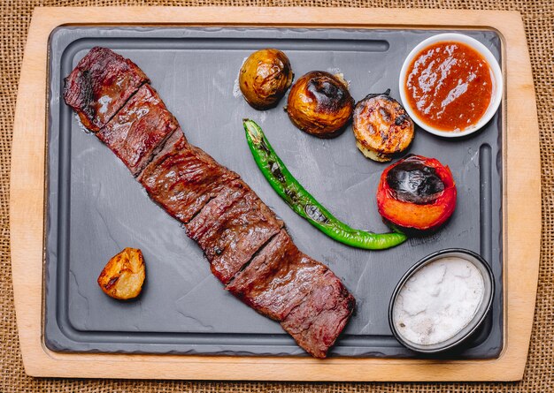 Top view grilled meat with potatoes and grilled vegetables with ketchup and mayonnaise