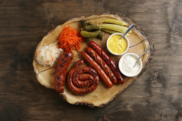 Top view of the grilled sausages with side dishes and sauces