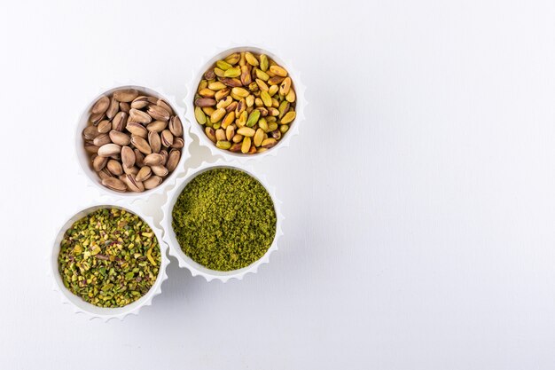 Top view ground, milled, crushed or granulated pistachios in a bowls on white  1