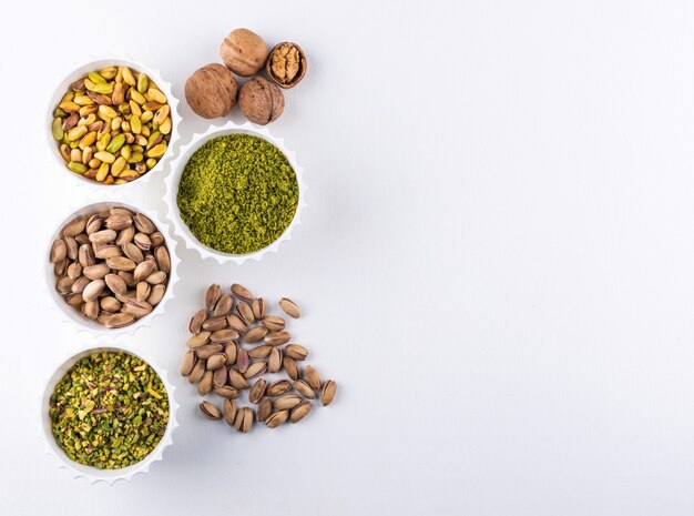 Top view ground, milled, crushed or granulated pistachios in a bowls on white