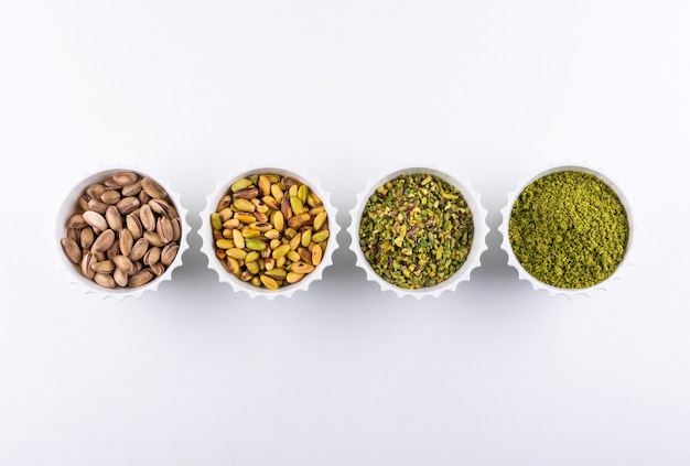 Top view ground, milled, crushed or granulated pistachios in a bowls on white 