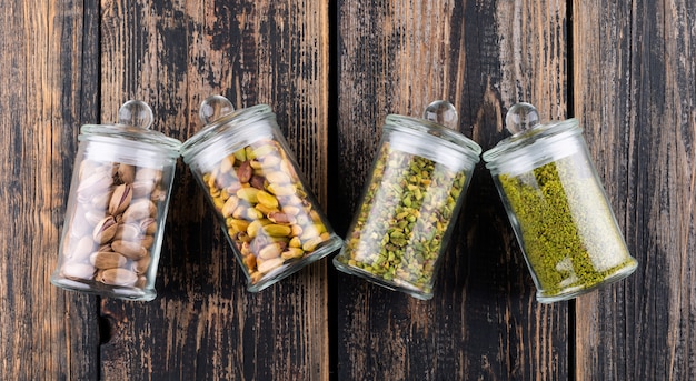 Top view ground, milled, crushed or granulated pistachios in glass jars on dark wooden 