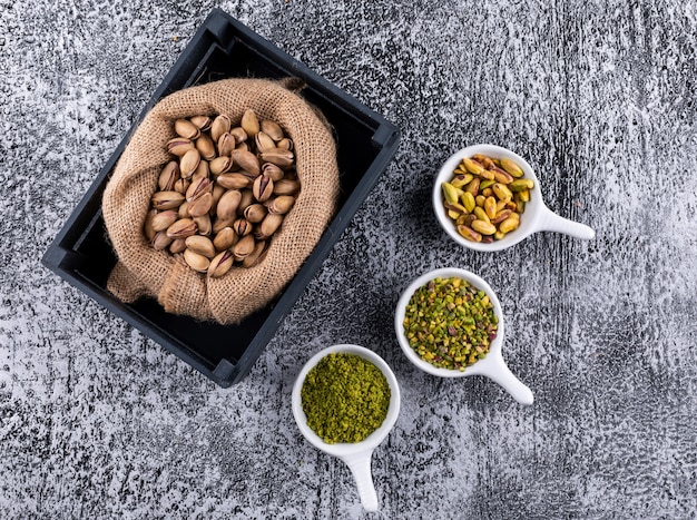 Pistacchi macinati, macinati, frantumati o granulati di vista superiore in sacco sull'orizzontale grigio del fondo di struttura