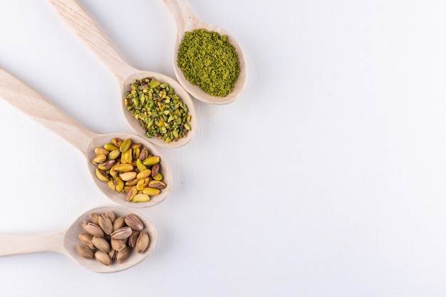 Top view ground, milled, crushed or granulated pistachios in wooden spoons on white