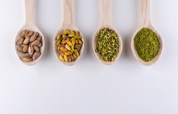 Top view ground, milled, crushed or granulated pistachios in wooden spoons on white 