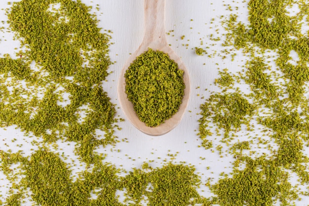 Top view ground, milled, crushed pistachios in wooden spoons on white 