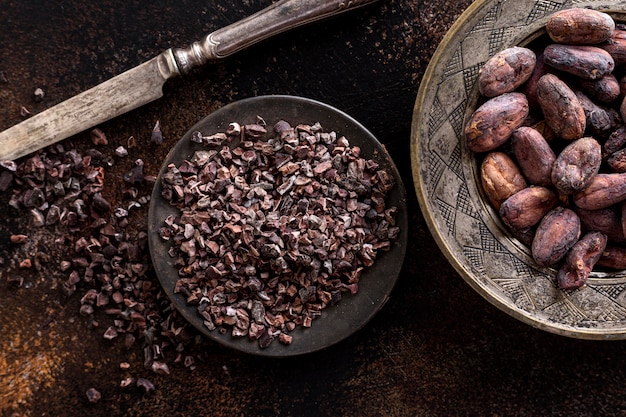 Top view of grounded cocoa beans on plate with knife and cocoa beans